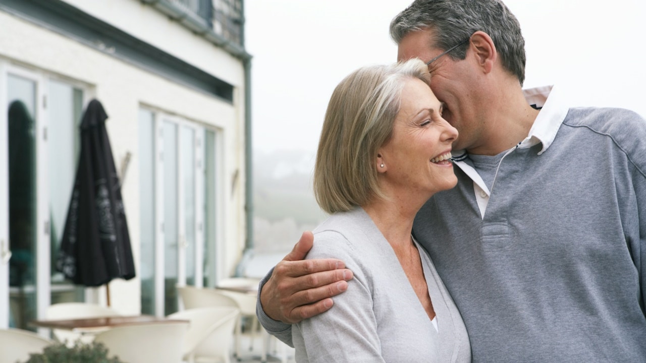 A man and a woman embracing outside a building.