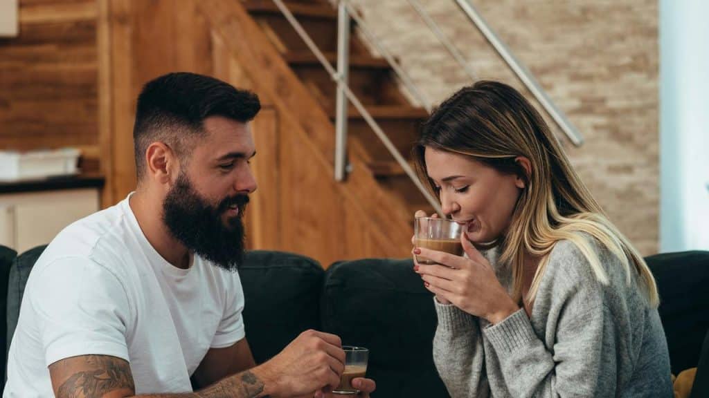 A couple sitting on a couch and enjoying warm drinks together.