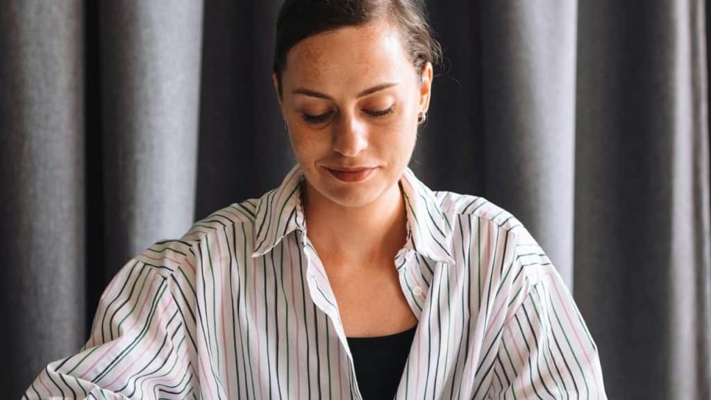 A woman in a striped shirt looking down at a table.