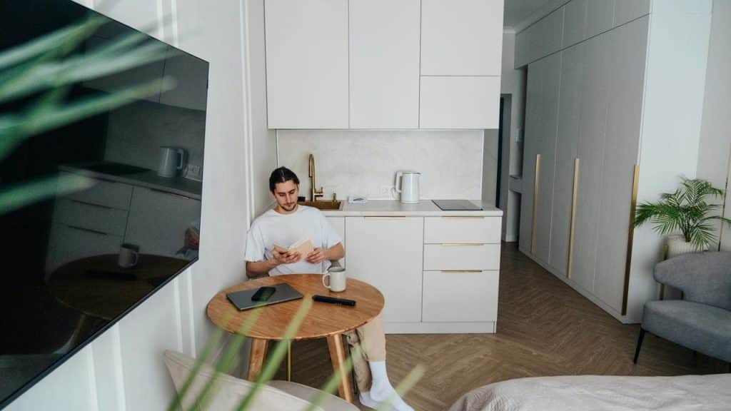 A man reading at a small table in a modern kitchen