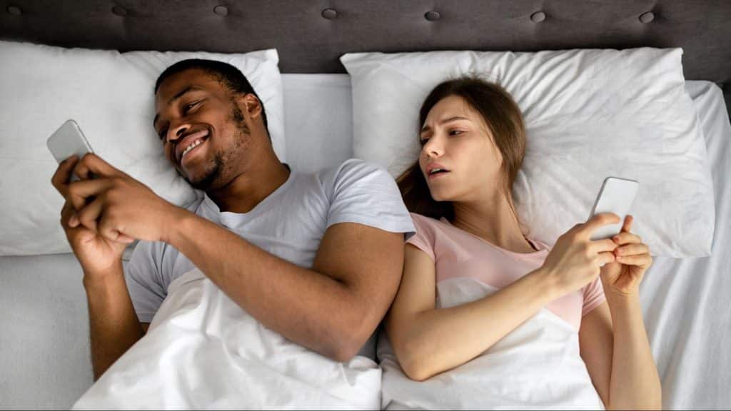 A man busy with his phone and a woman looking at it