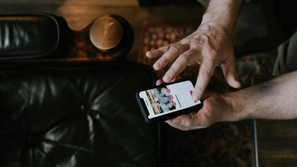 A close-up view of hands holding a smartphone displaying a social media profile of Samantha.