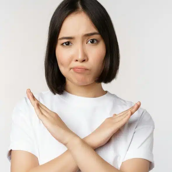 A woman with a displeased expression crossing her arms in an “X” gesture.