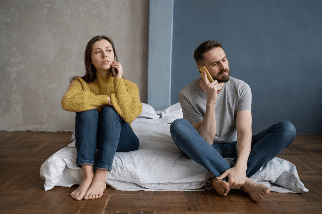 Couple sitting on floor using phones