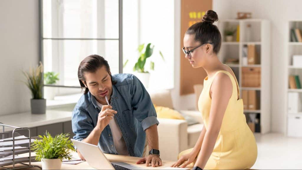A man busy working and a woman trying to talk to him 