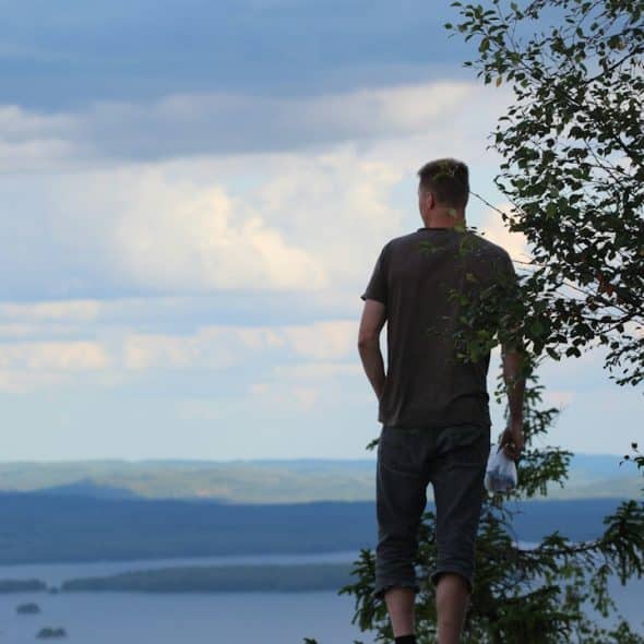 A man standing on a cliff overlooking a picturesque view.