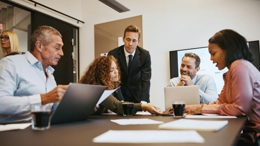 A diverse group of professional colleagues collaborating around a table in a bright office.