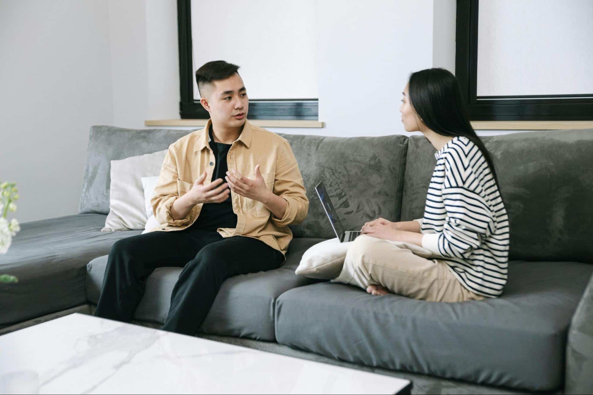 A man and a woman are on the couch, talking