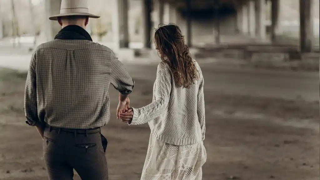 A man and a woman holding hands while walking outdoors.