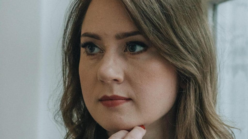 A woman with brown hair resting her chin on her hand.