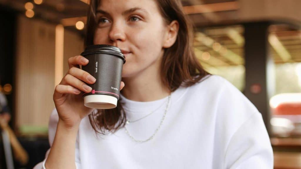 A woman holding a takeaway coffee