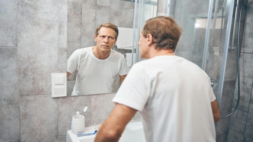 man looking thoughtful in mirror