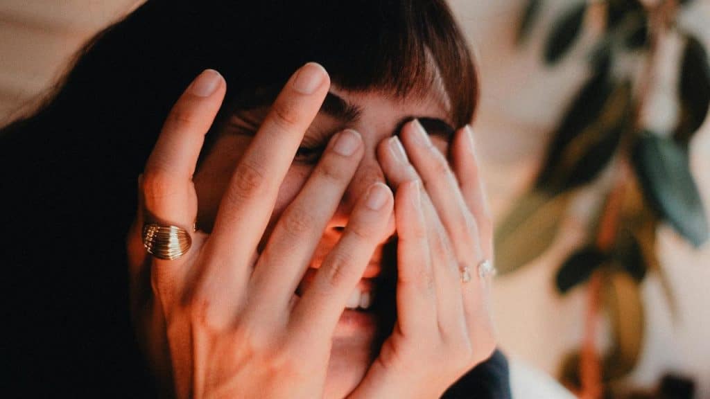 A woman covering her face with her hands.