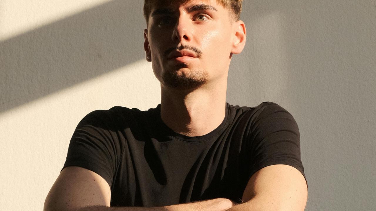 A man with crossed arms standing against a wall