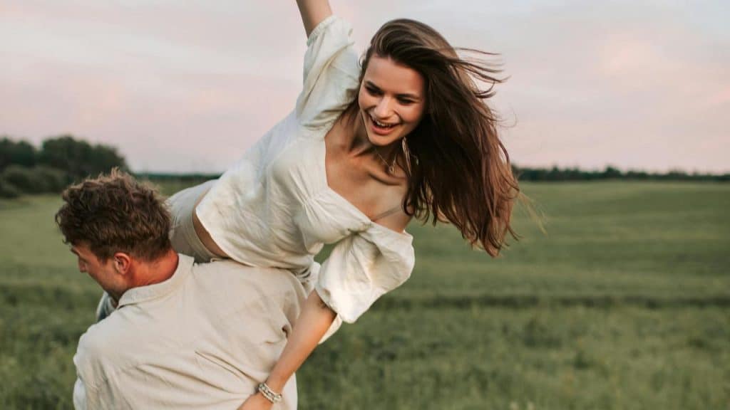 A man carrying a woman on his back in a field