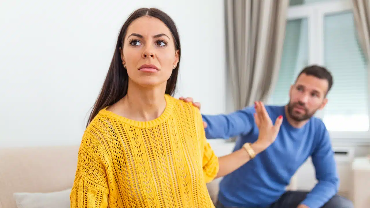 A man is apologizing to his angry wife, who is ignoring him.