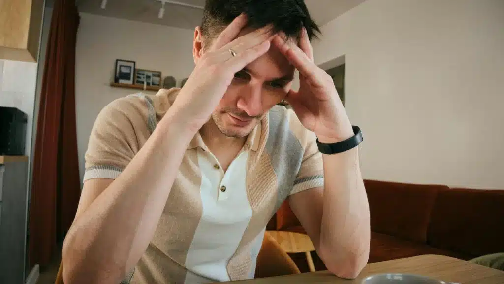 A man sits with his hands on his head