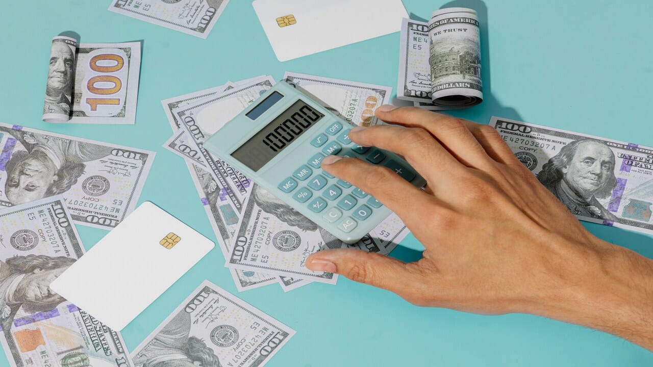A person holding a calculator with a pile of money