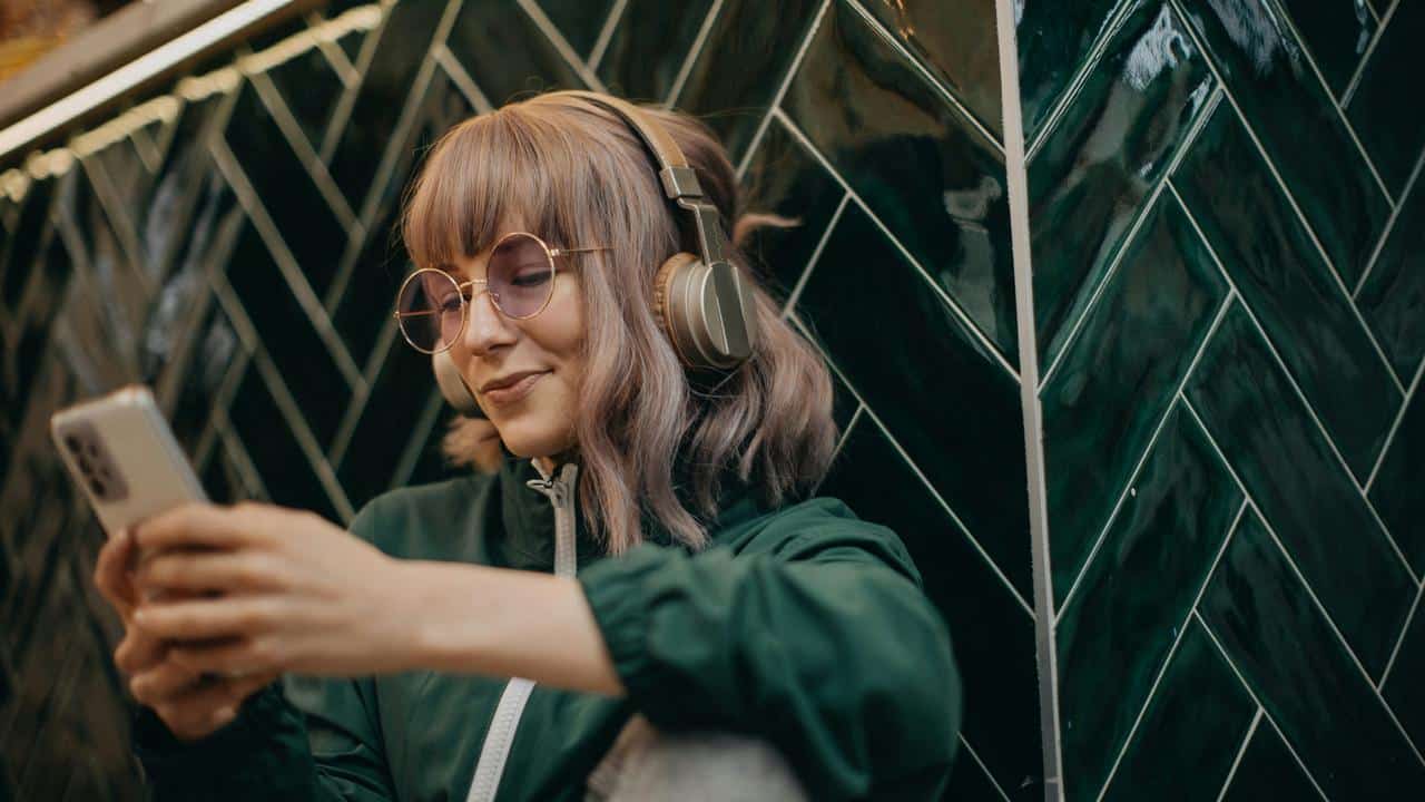 A woman wearing headphones and using her phone