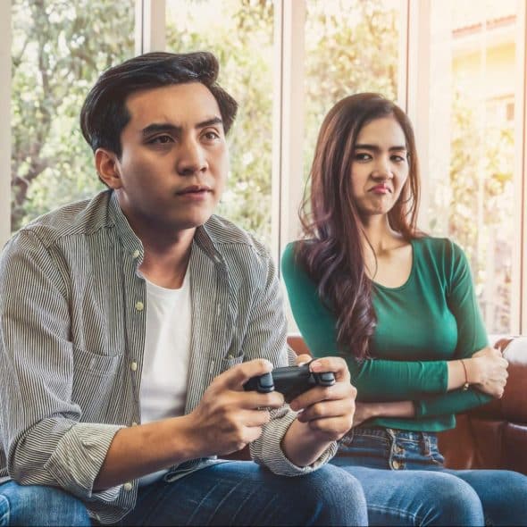A man playing games and a woman, annoyed with it