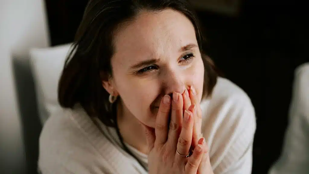 A distressed woman covering her mouth with her hands.