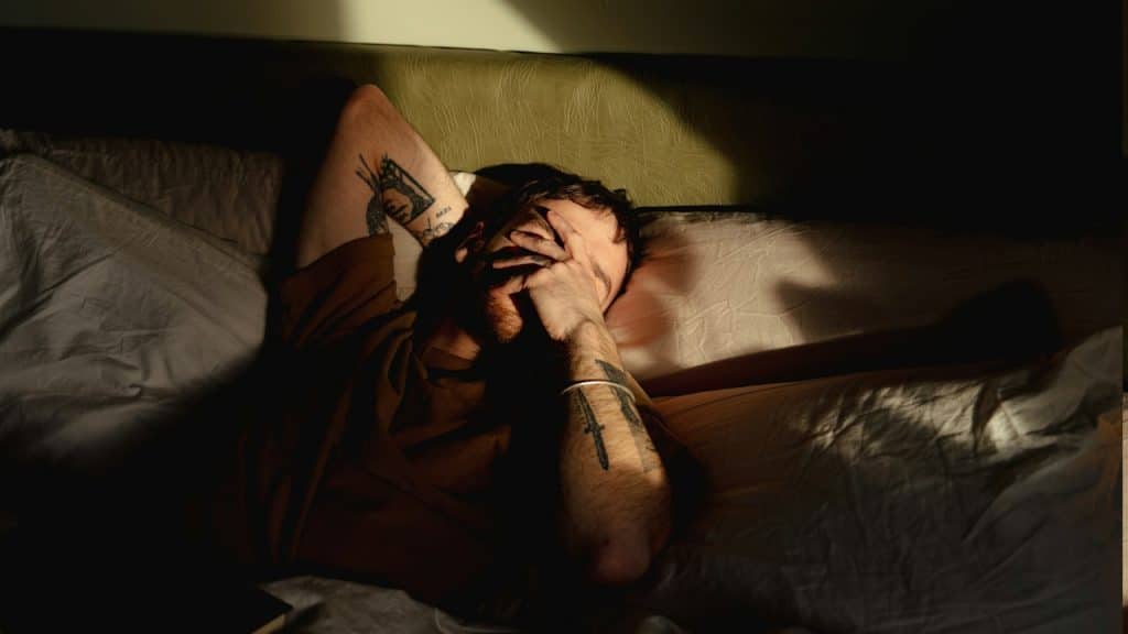 A man lying in bed with his head on his hands.
