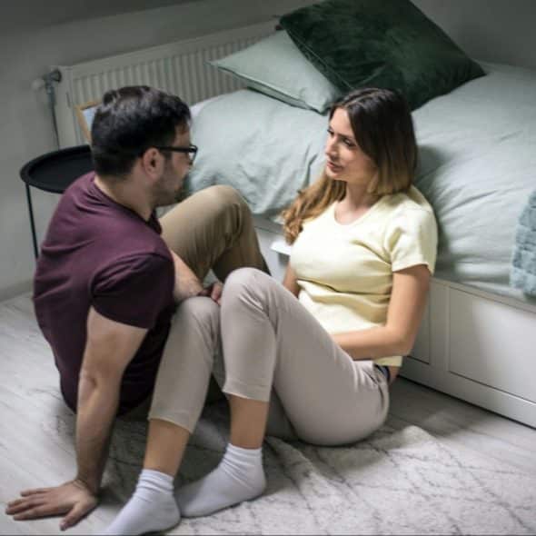 A man and a woman are talking while on the floor
