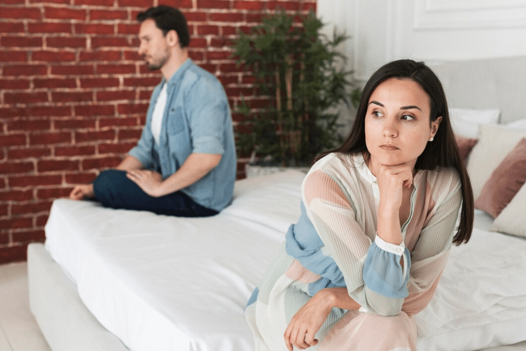 Unhappy couple sitting apart on bed
