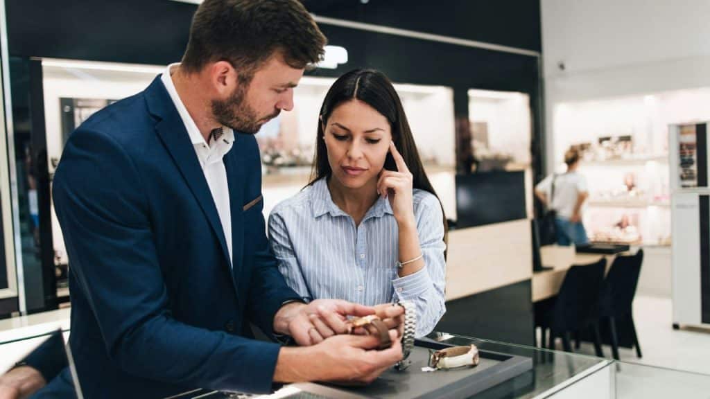 A man and a woman look at wristwatches together inside a jewelry store.