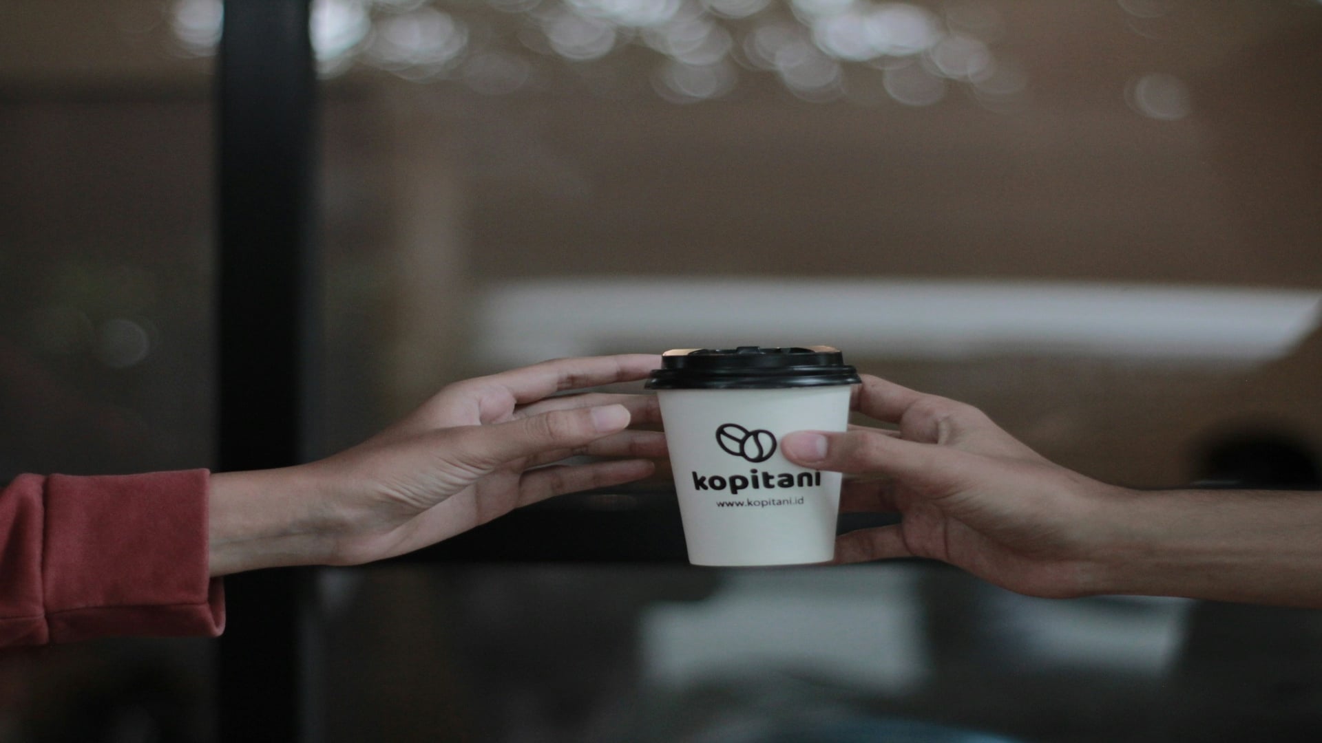 person handing coffee to partner