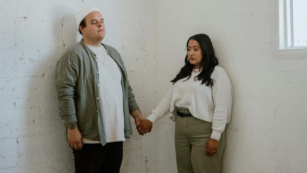 A man and a woman holding hands while standing in an empty room.