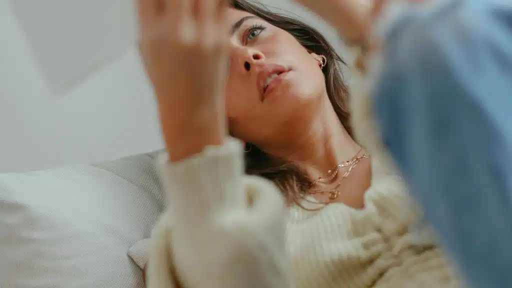 A woman lying down and looking at her phone.