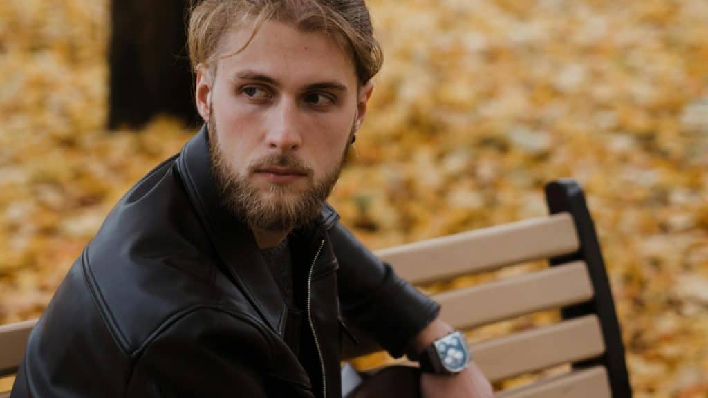 A man sitting on a park bench looking to the side.
