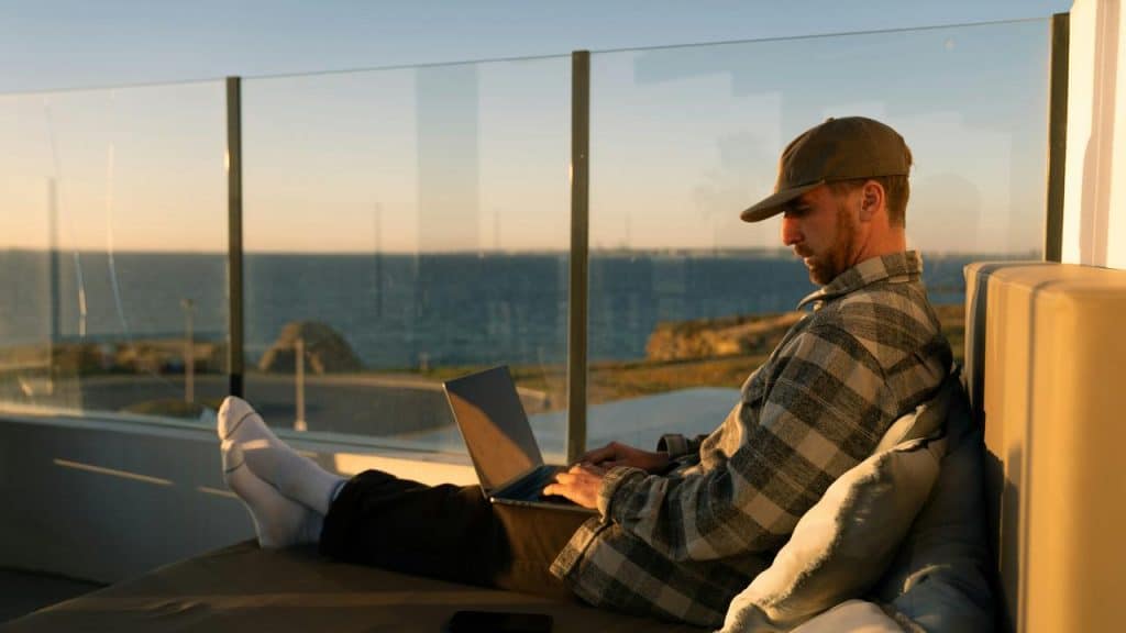A man using a laptop while relaxing by the seaside.