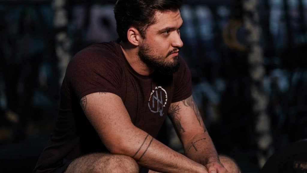 A muscular man resting in a gym.