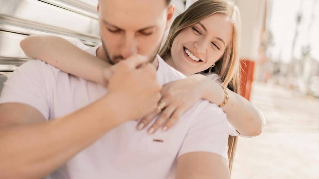 A smiling woman hugs a man from behind
