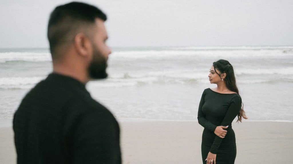 A couple wearing black dresses are standing on the beach.