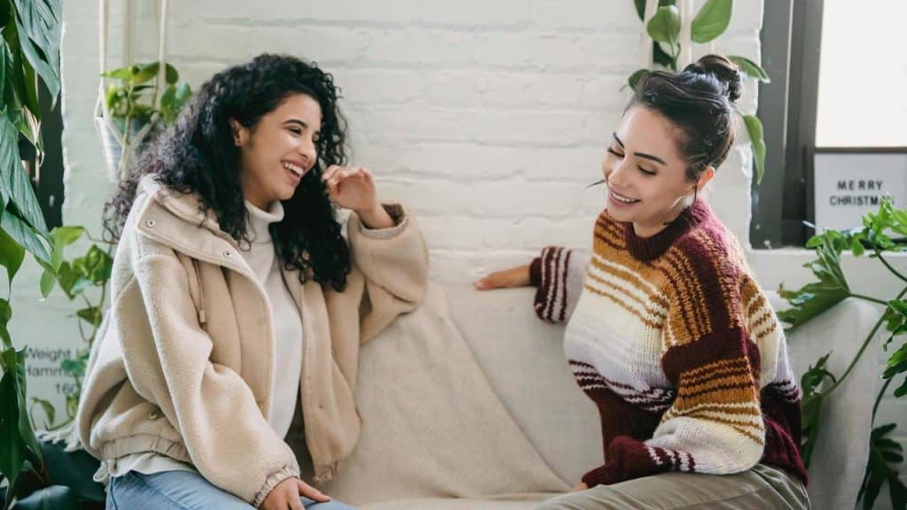 A pair of people sitting on a couch laughing together.