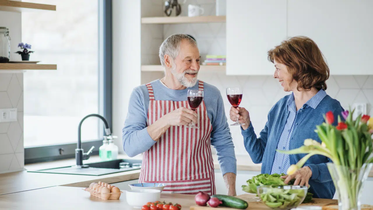 A couple clinking glasses in the kitchen