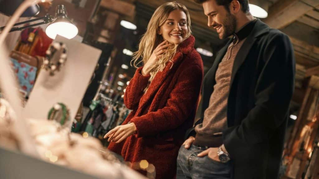 A man and woman smiling while shopping for jewelry at a market.