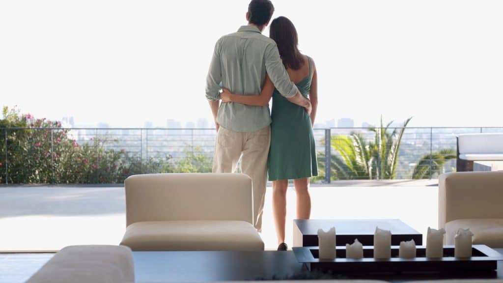 A couple standing together on a balcony overlooking the city.