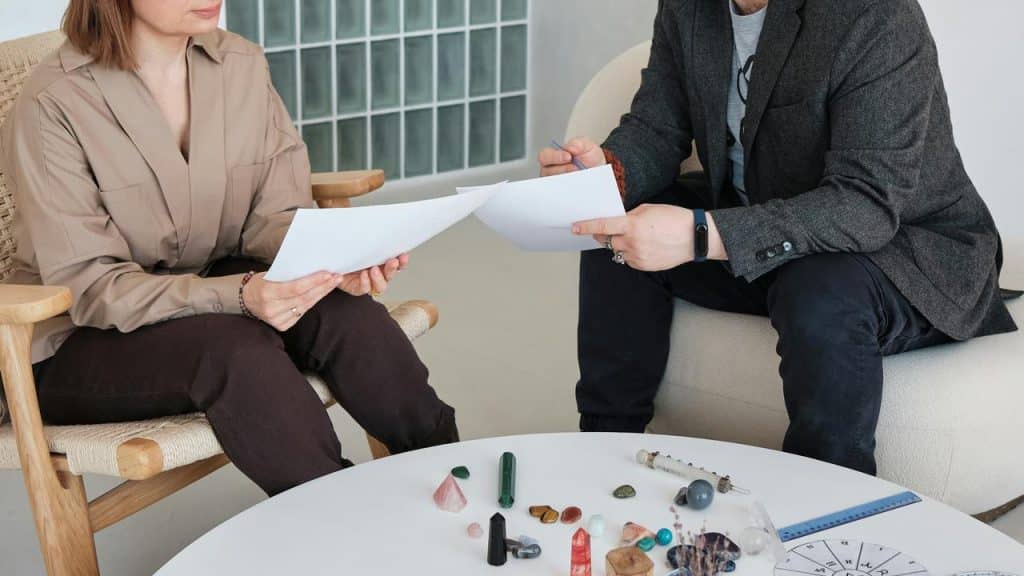 A pair of people reviewing documents while seated at a table with crystals.