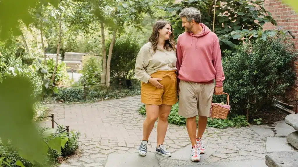 A couple walking together in a garden, smiling at each other.