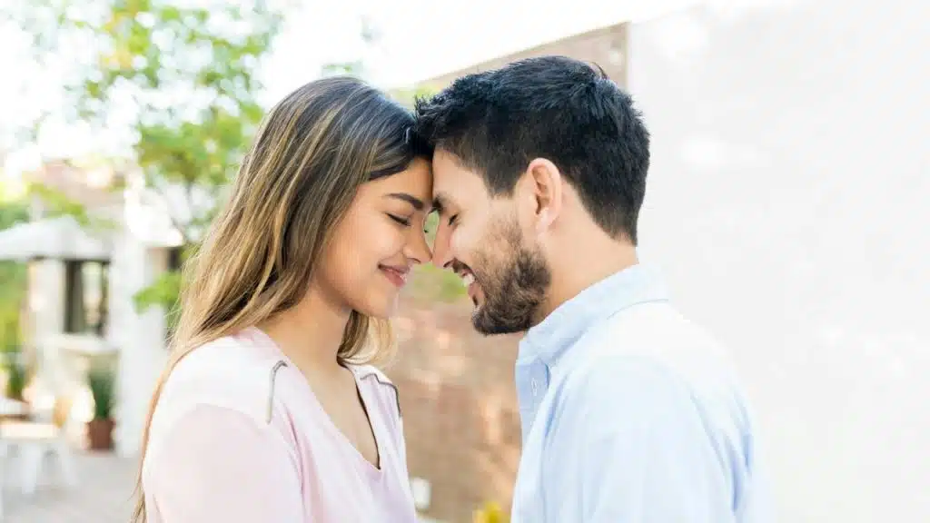 Side view of a romantic couple touching foreheads during a date.