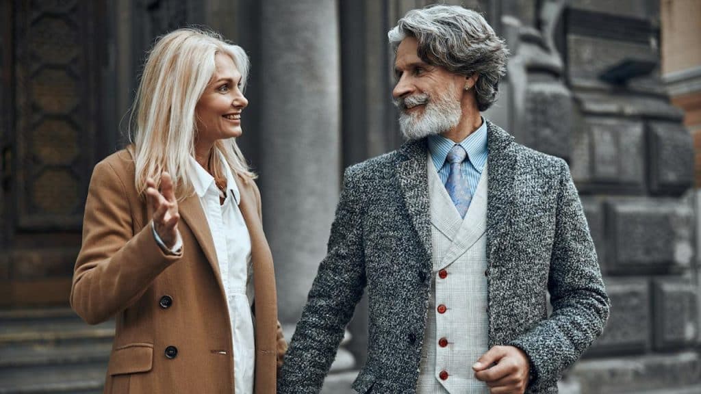 A bearded man looking back at a woman who’s gesturing with her hand and smiling at him.