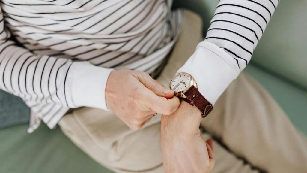 A person checking the time on a wristwatch while sitting down.