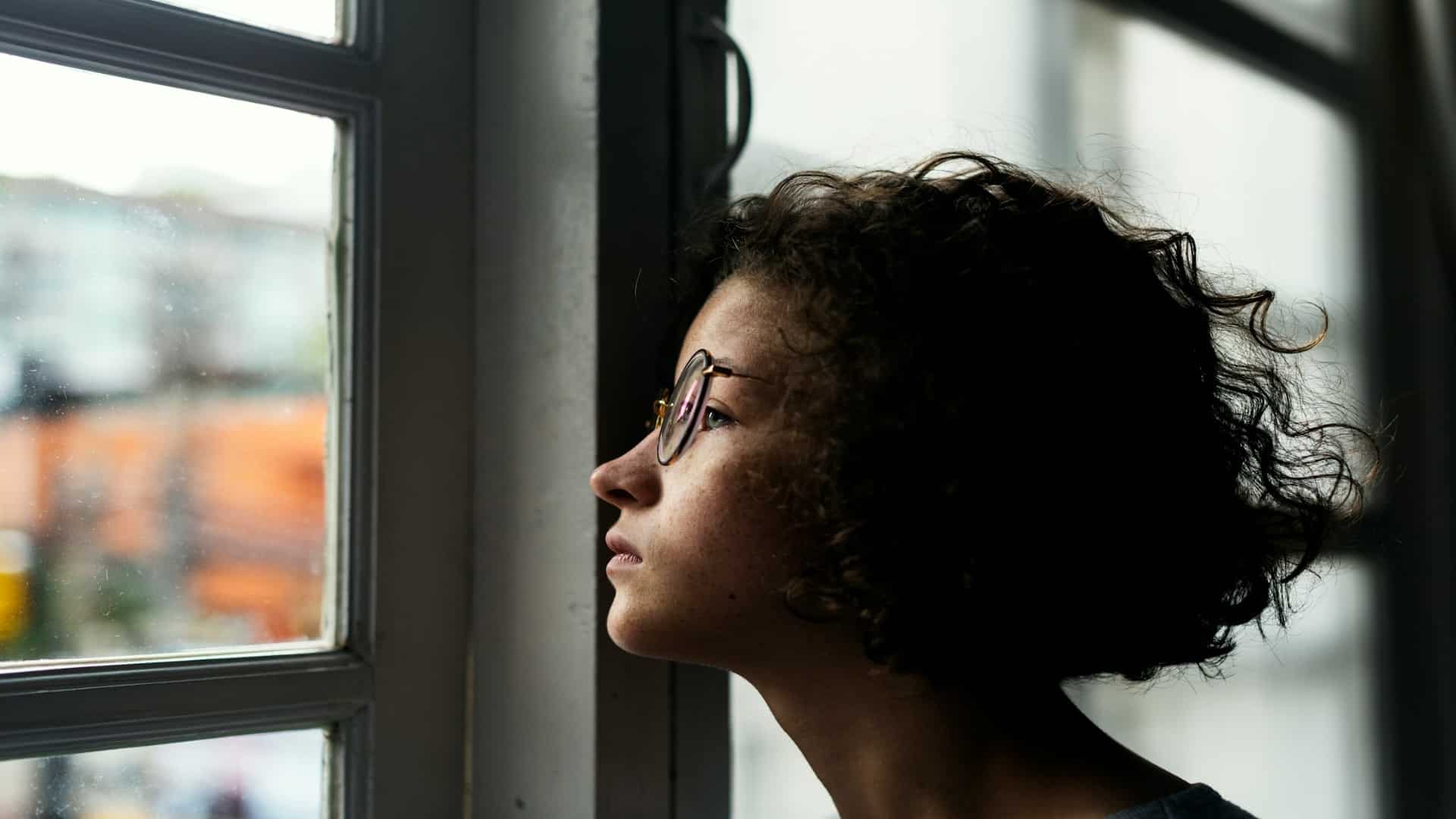 person looking thoughtful near window