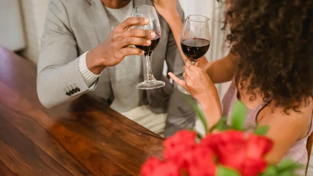 A couple clinking glasses of red wine during a dinner date.