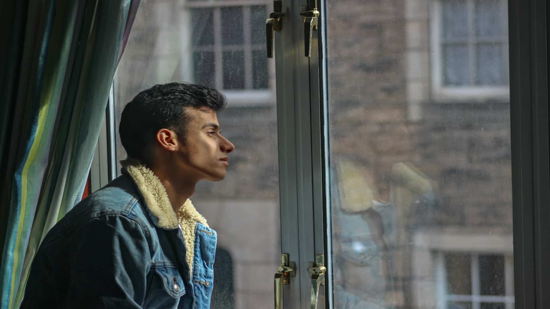 man sitting thoughtfully looking out window