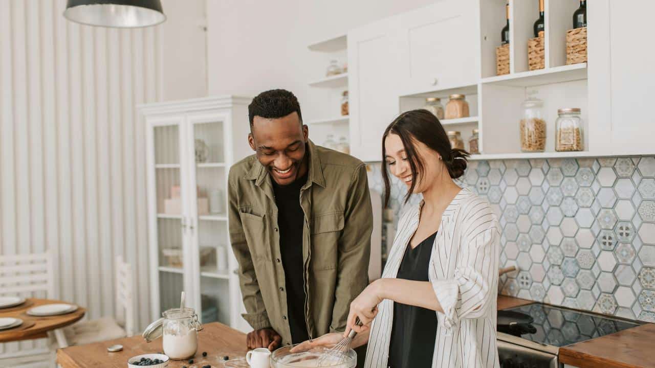 A couple smiling and cooking together
